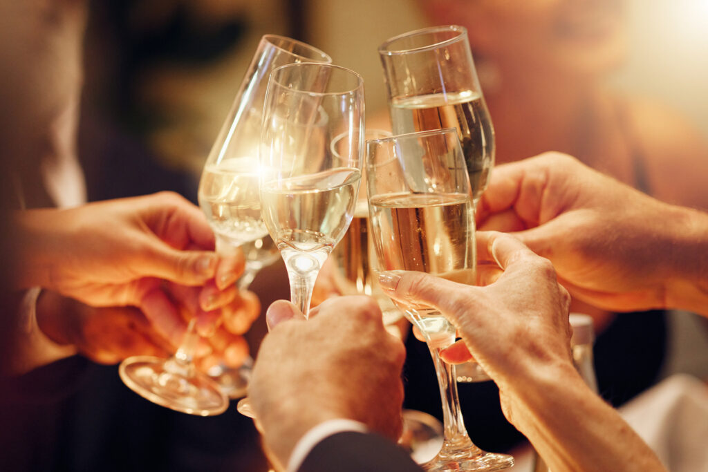 A group of people raising champagne glasses for a toast, with a warm golden glow capturing the festive and celebratory New Year’s atmosphere.