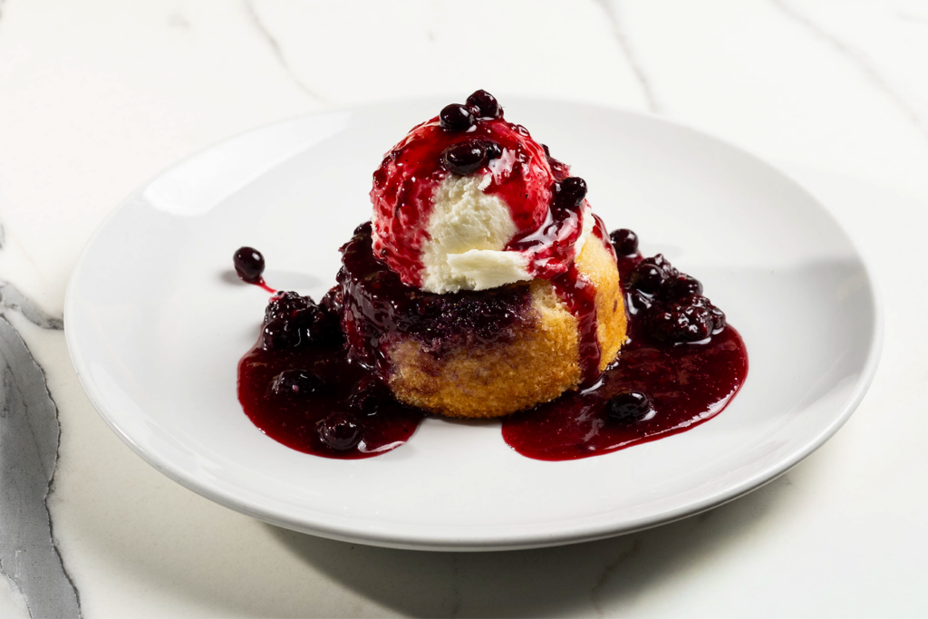 Warm berry cake topped with ice cream and berry sauce.