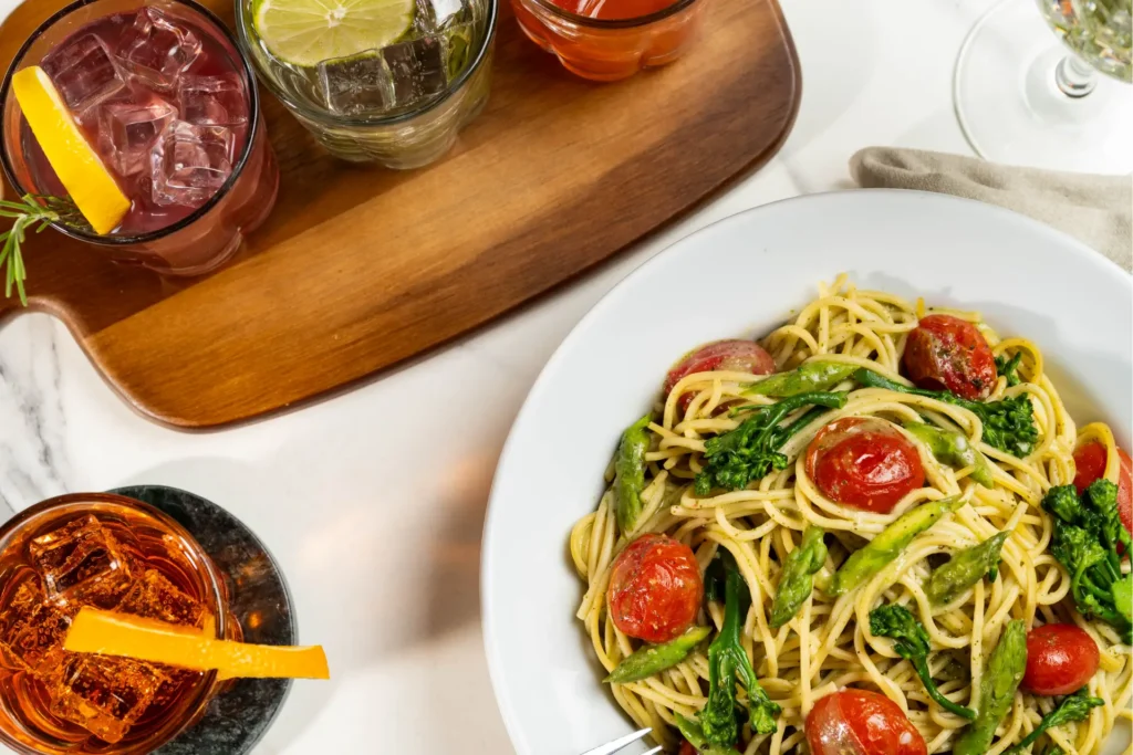 Spaghetti with asparagus, broccolini and tomatoes served with cocktails.